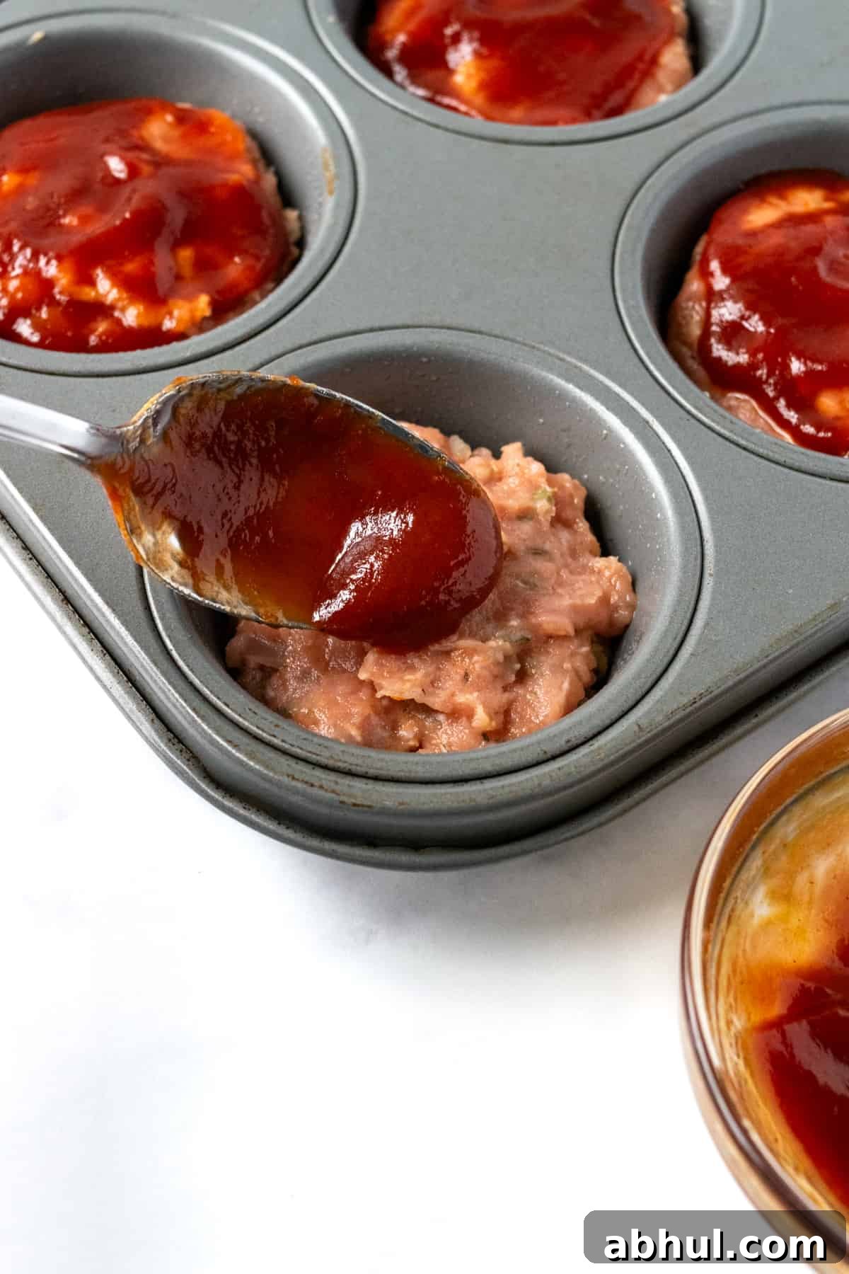 Spooning Sauce Over Turkey Meatloaf Muffins.