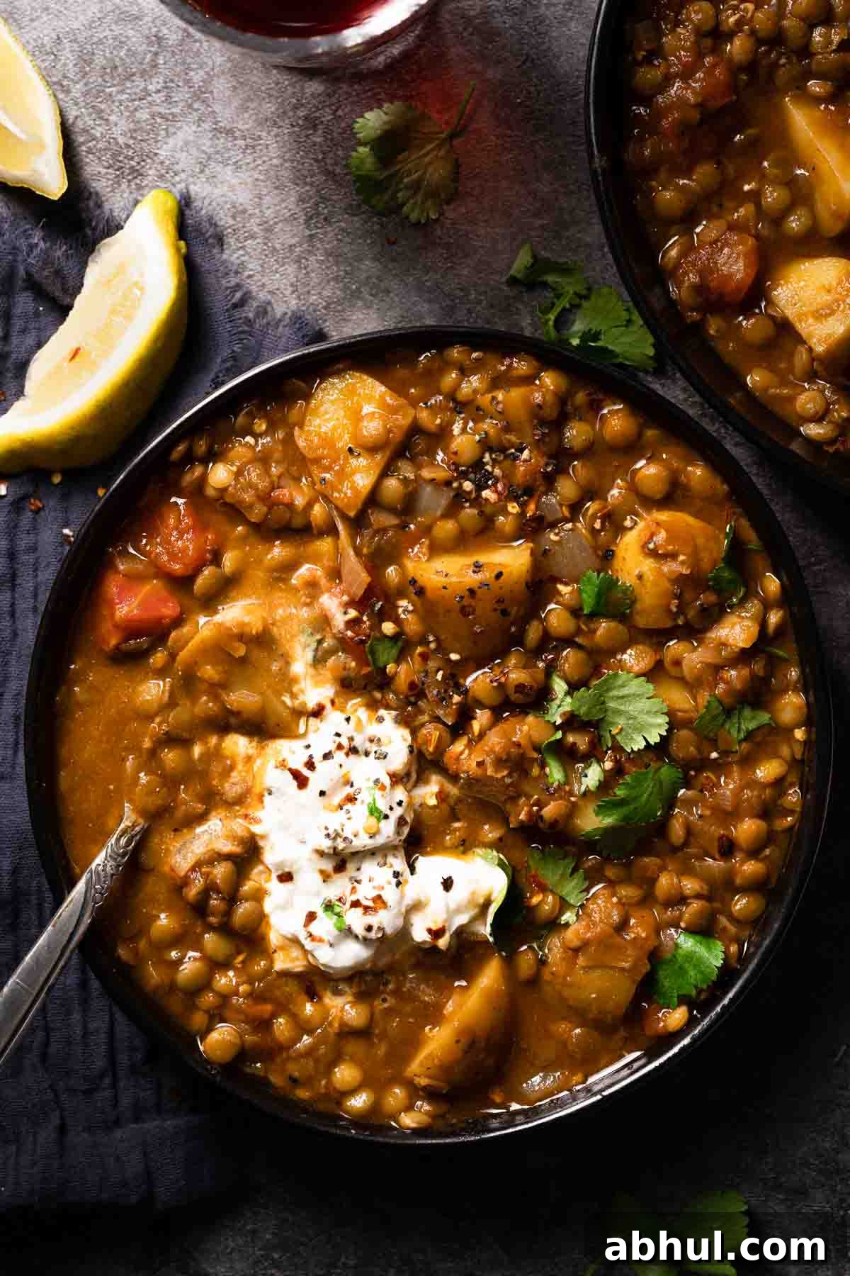 lentil potato soup in two bowls with spoon in bowl and two lemon wedges on the side