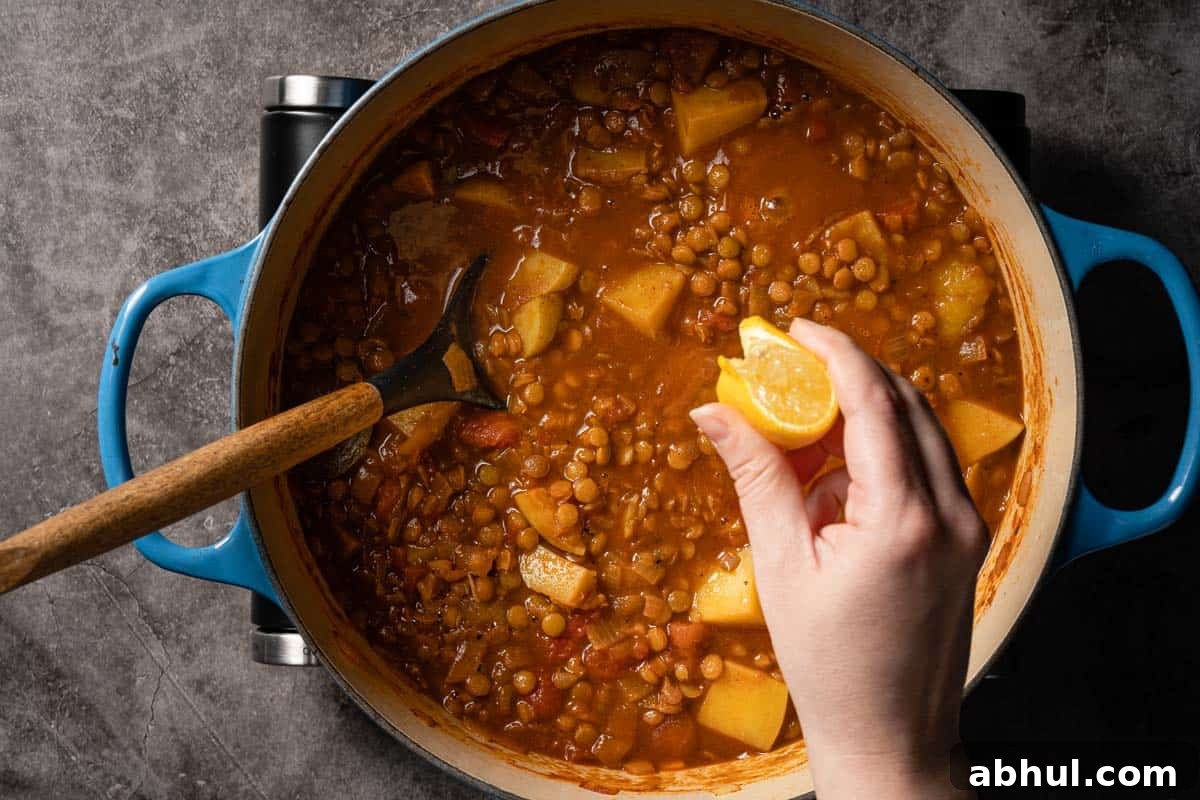 lemon wedge being squeezed over soup in pot