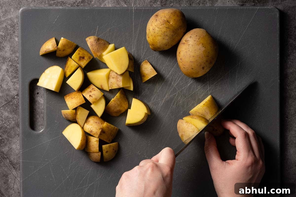 potatoes being cut into chunks on cutting board