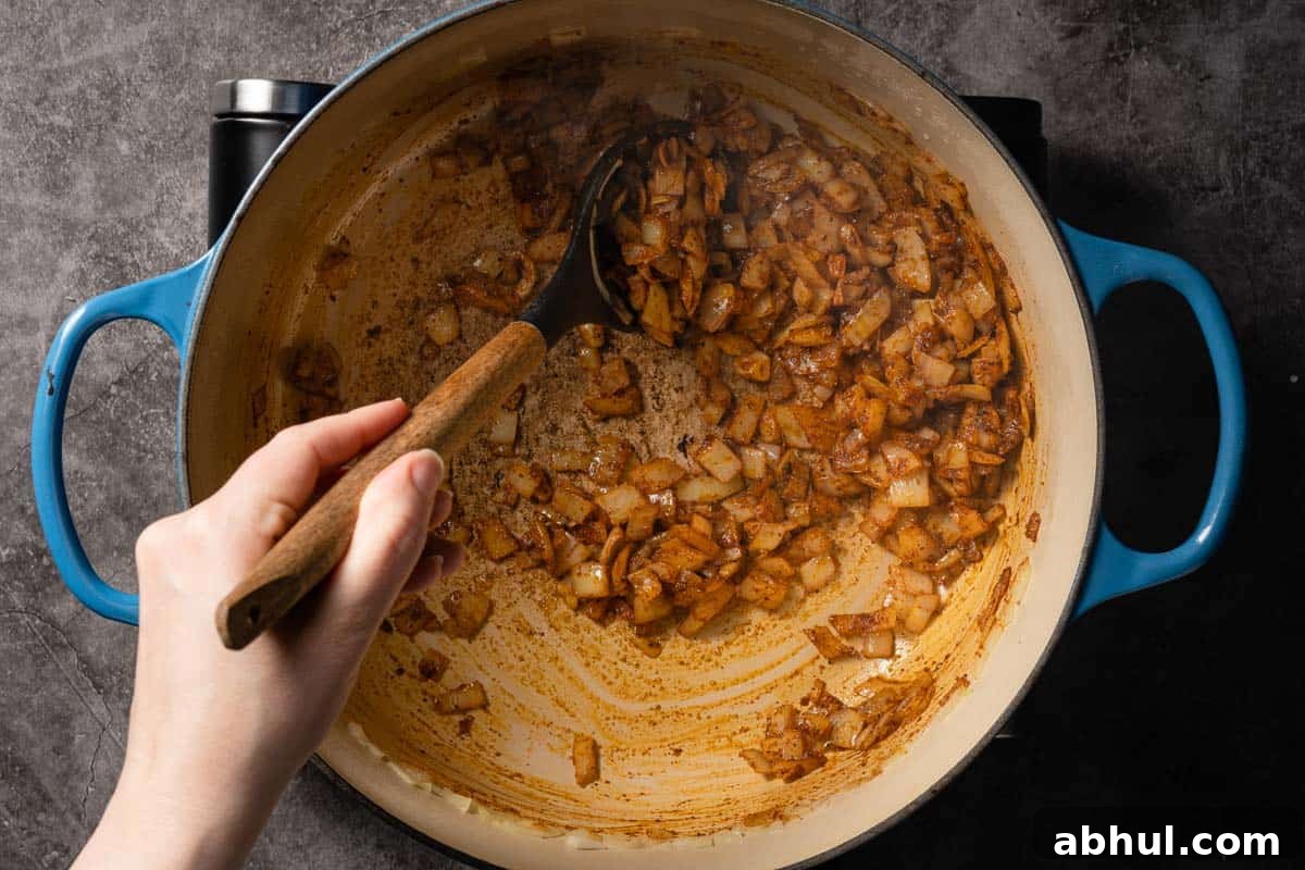 onion and spices being stirred in soup pot