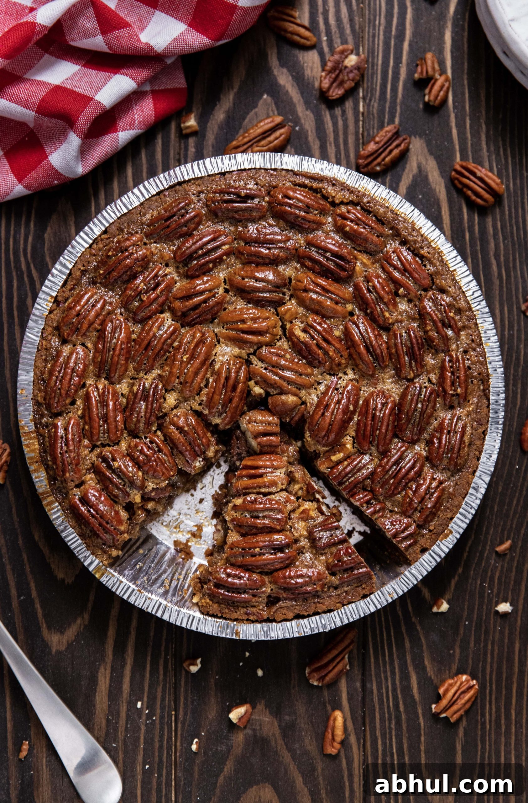 Bourbon pecan pie on wood tabletop with a slice missing