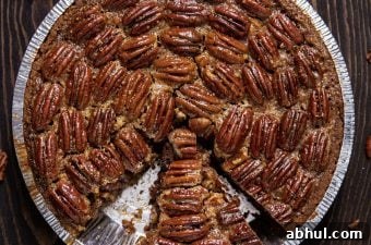 Bourbon pecan pie on wood tabletop with a slice missing