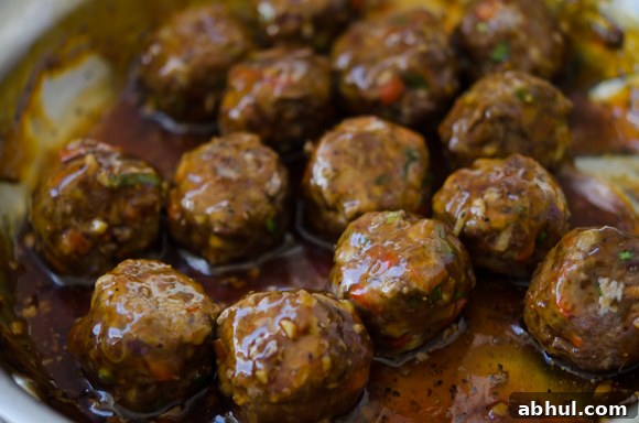 Baked Asian-style meatballs simmering in tangy pineapple glaze