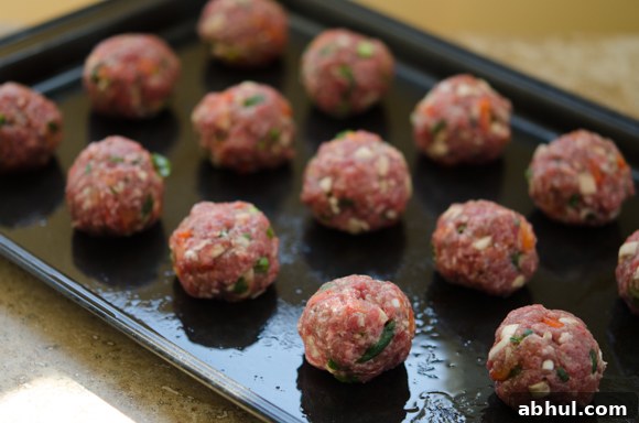 Formed beef meatballs placed on a baking tray before cooking