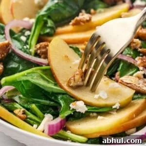 Spinach and Apple Salad with Maple Walnut Dressing 2 A fork in a apple slice in a apple spinach salad