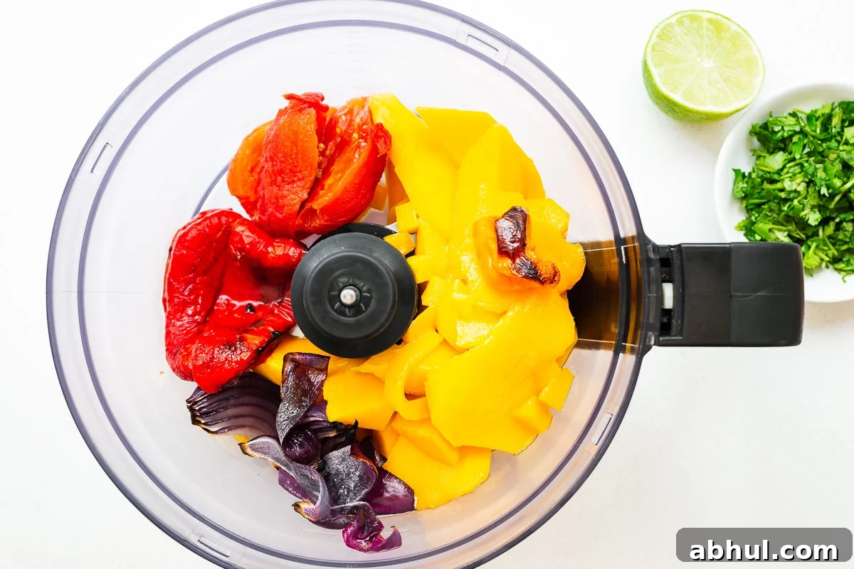 Ingredients for roasted mango salsa in a food processor.