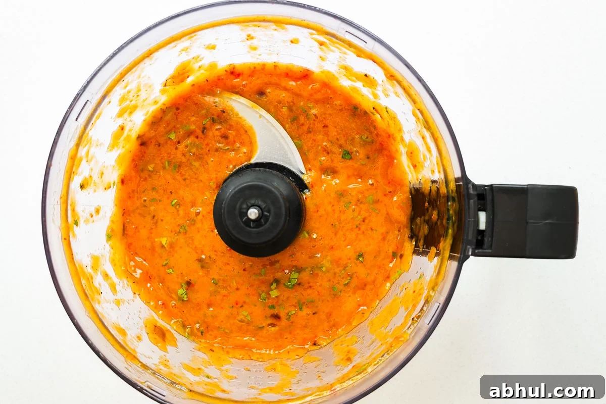 Spicy roasted mango salsa in a food processor with a smooth sauce-like consistency.