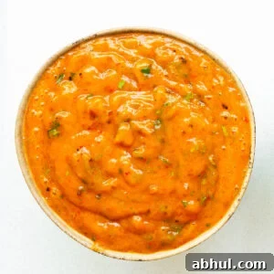 A bowl of vibrant orange roasted mango salsa with a smooth consistency.