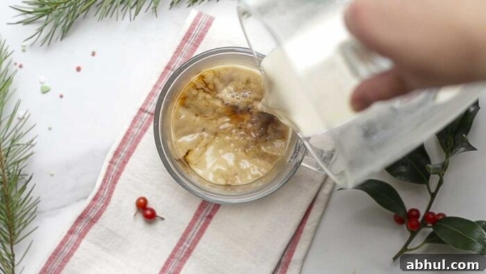 pour eggnog over coffee in a mug on a cream and red stripped towel.