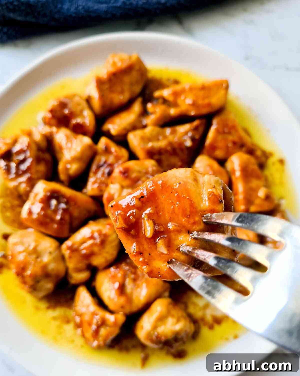 A piece of butter honey glazed chicken on a fork