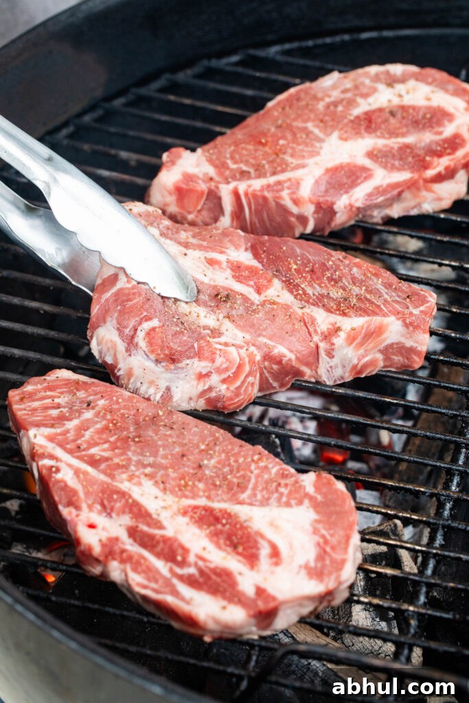 placing three pork coppa steaks on the grill over lit coals