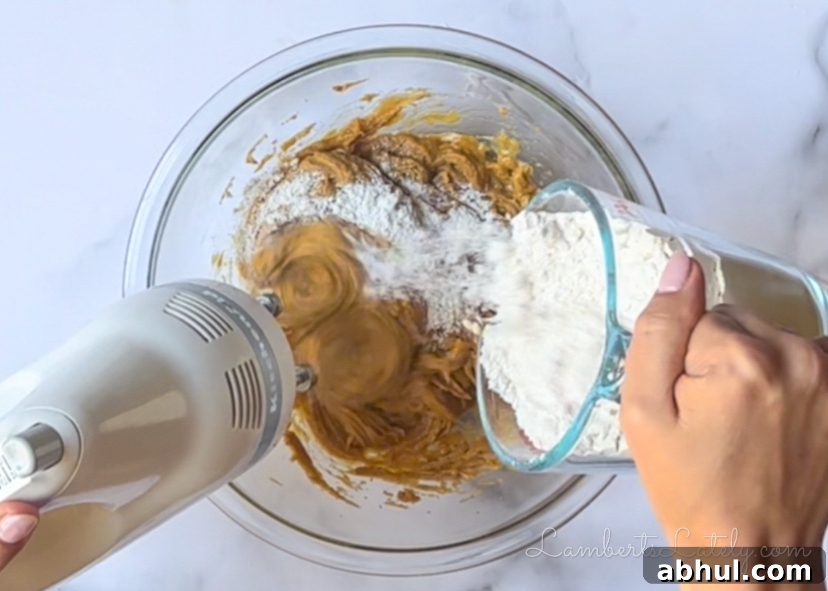 adding flour to the wet ingredients in a large glass bowl.