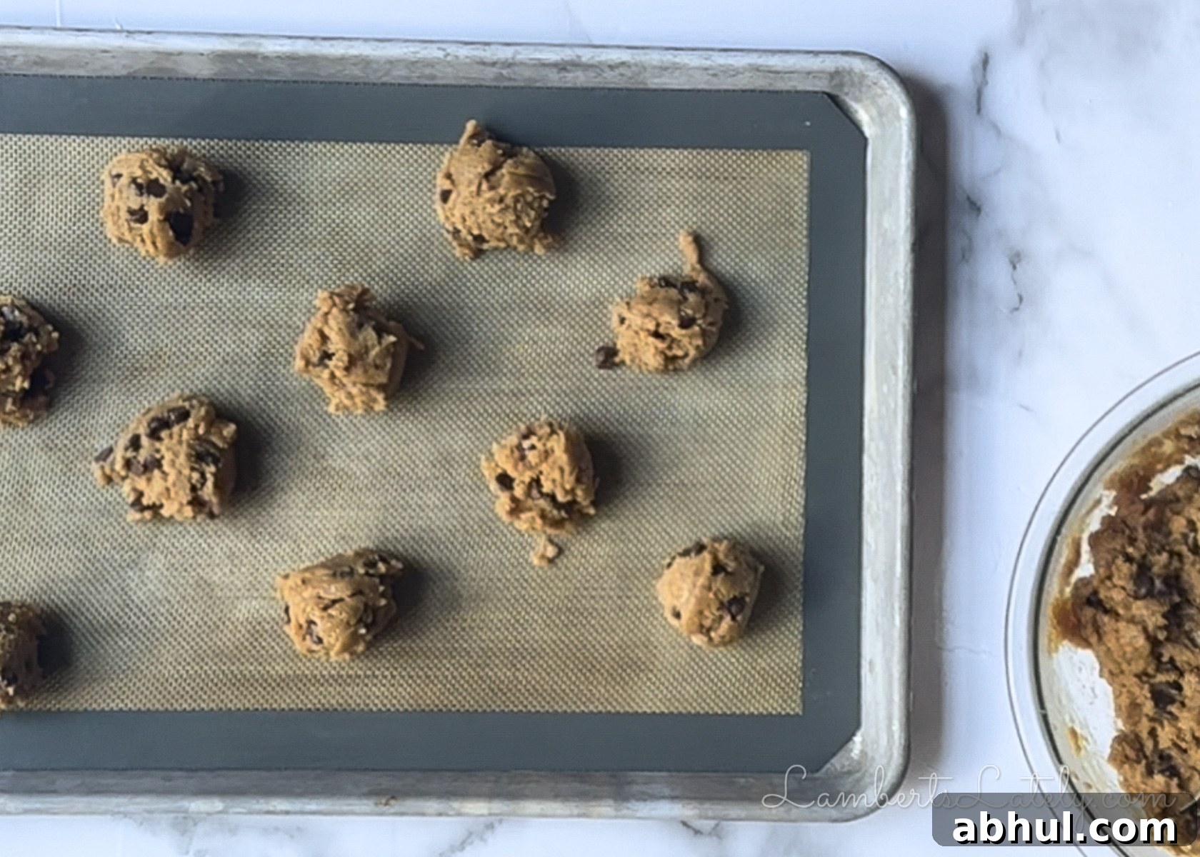 2 tablespoon scoops of peanut butter chocolate chip cookie dough on a lined baking sheet.