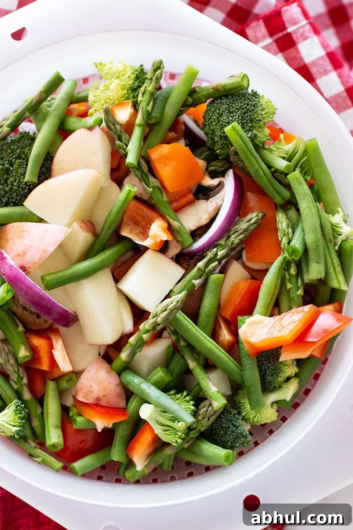 Sheet Pan Sausage with Roasted Vegetables Recipe 4 Colander of fresh chopped vegetables on a marble counter.