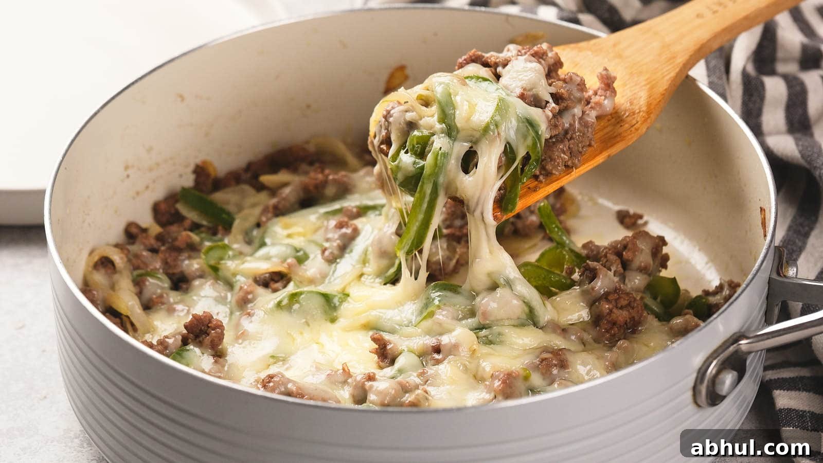 Image shows a wooden spatula cutting philly cheesesteak casserole from baking dish.
