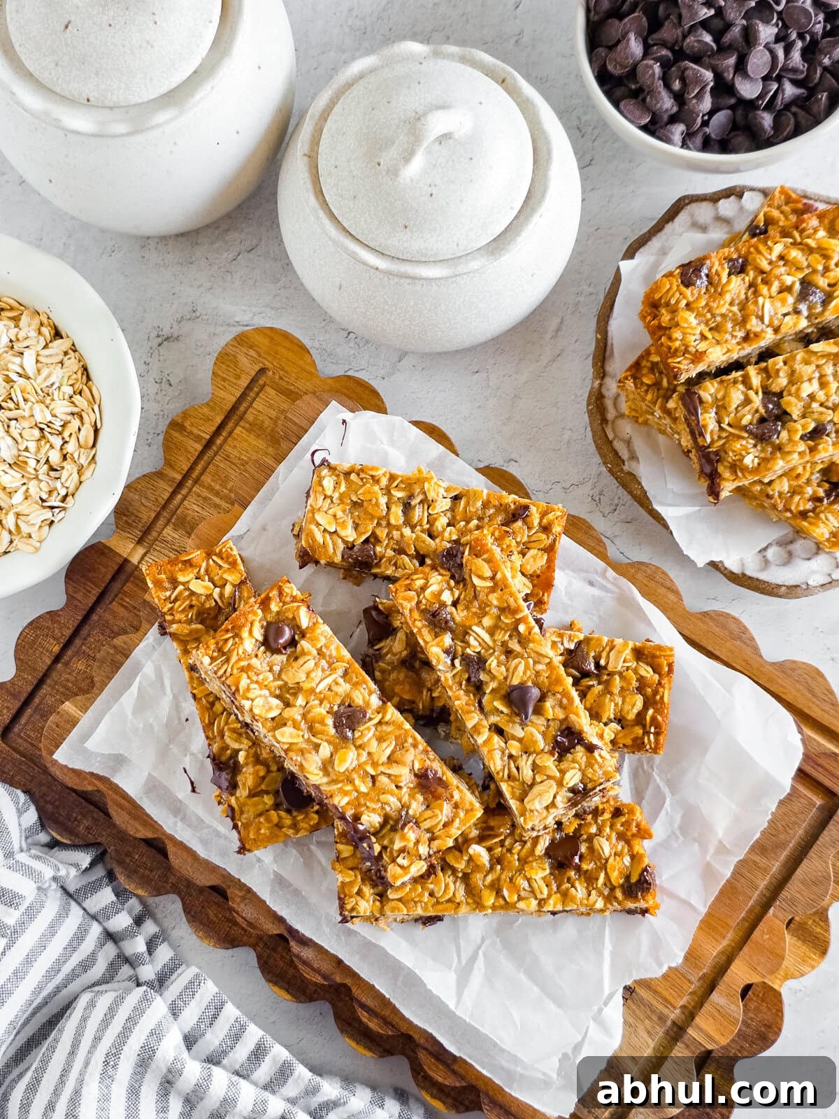 Chewy Einkorn Granola Bars with chocolate chips on parchment paper, on a wooden cutting board.