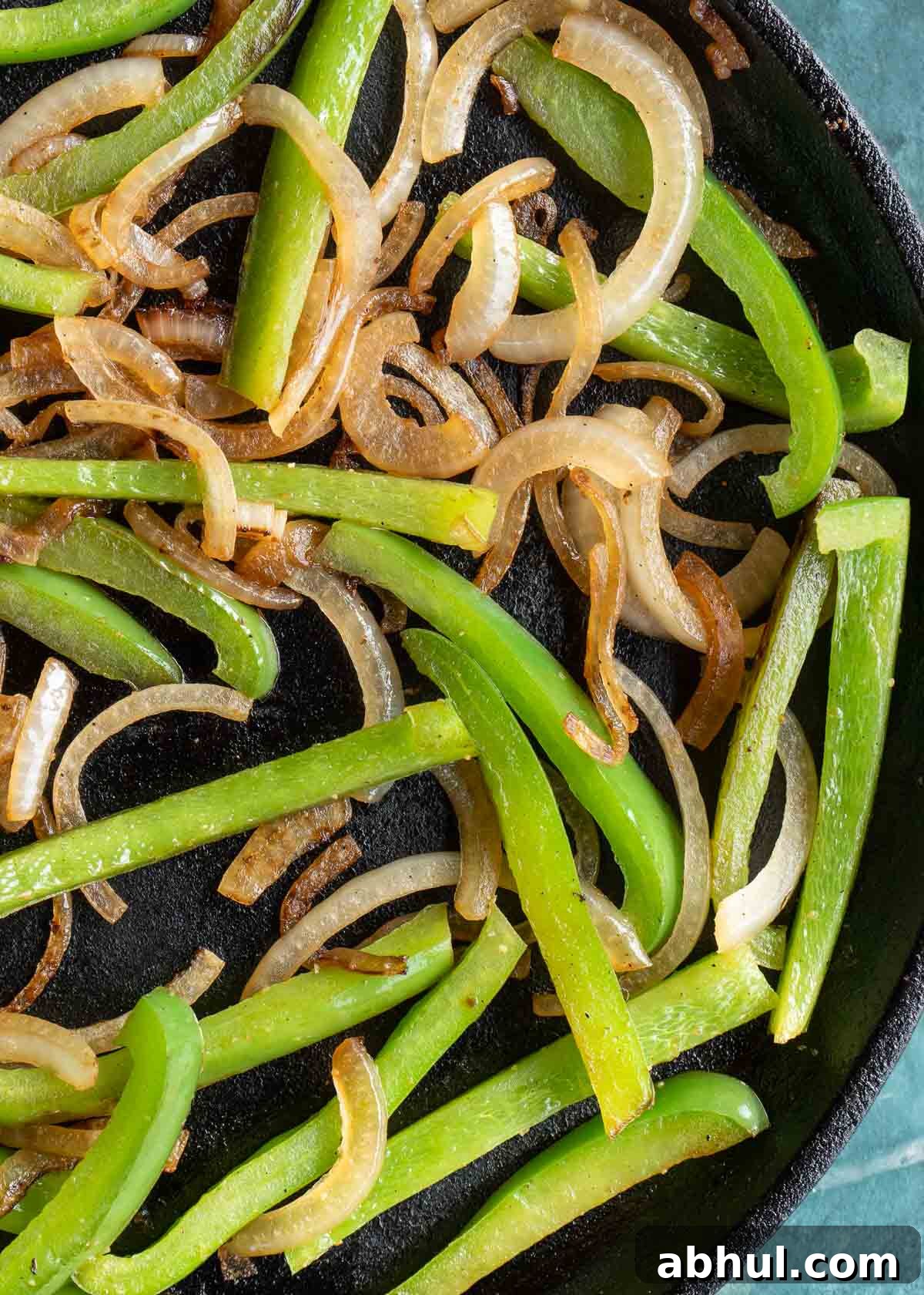 Philly Cheesesteak Wrap Recipe: Quick Steak & Cheese Wraps 4 strips of onion and peppers cooking in a skillet