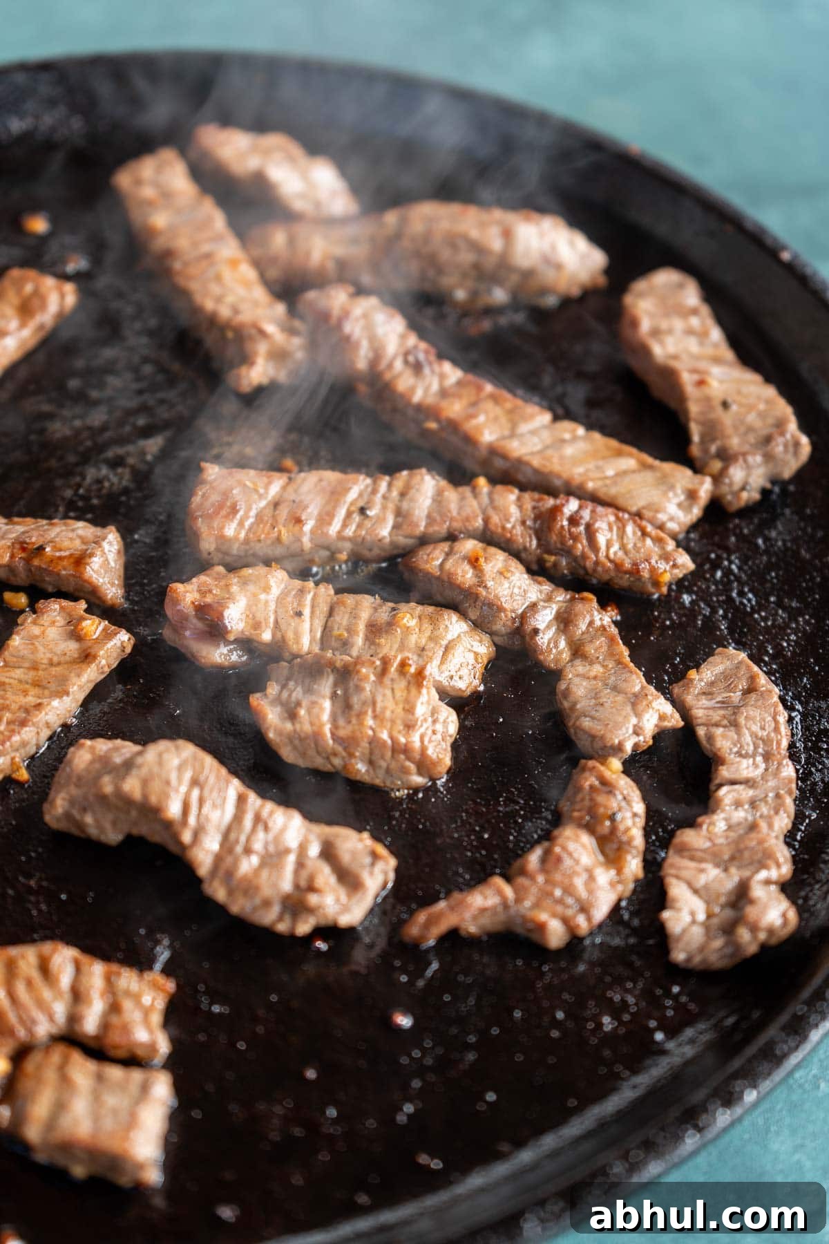 Philly Cheesesteak Wrap Recipe: Quick Steak & Cheese Wraps 5 Strips of marinaded sirloin steak cooking on a skillet for an easy steak wrap