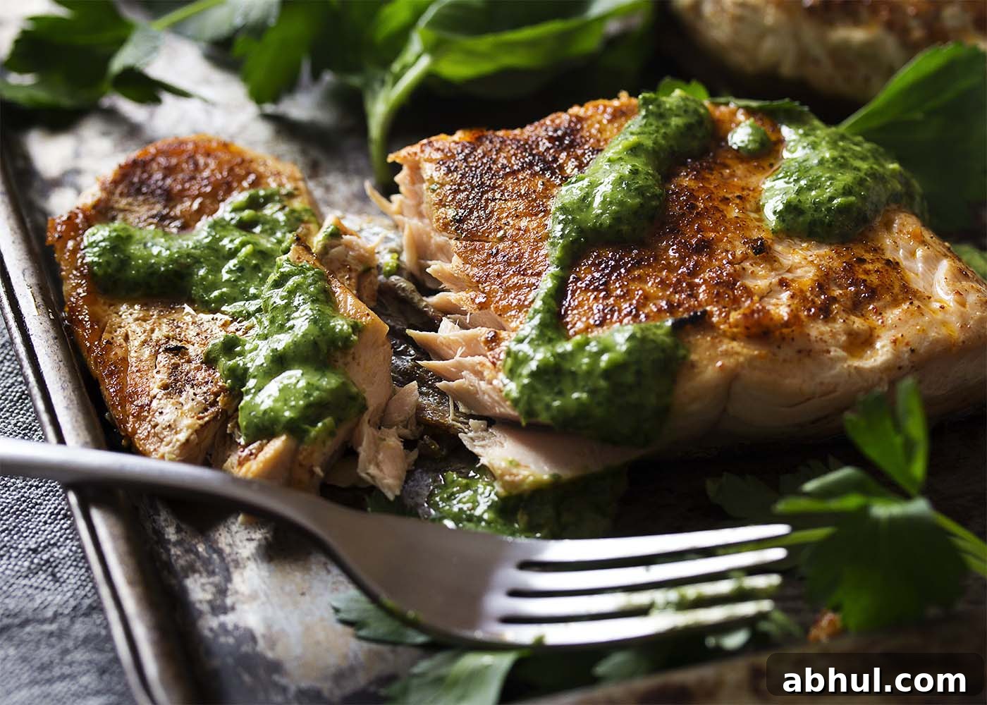 Crispy salmon fillet cut open with a fork showing that is tender and juicy.