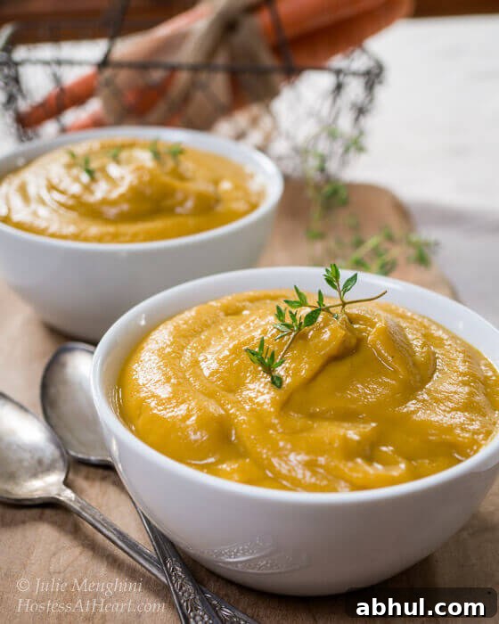 A creamy vegetable soup is not only easy but delicious and healthy too. This soup can also be used as a base for many other recipes. Two white bowls of creamed vegetable soup with a wire basket containing carrots in the background.