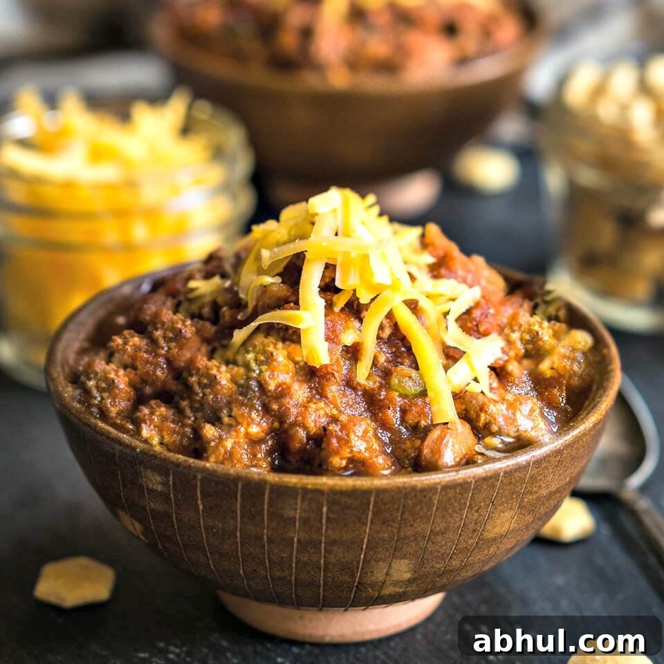 Roasted Vegetable Cream Soup Recipe – Velvety Homemade Flavor 5 Side view of a brown bowl heaped with beef chili topped with cheddar cheese.
