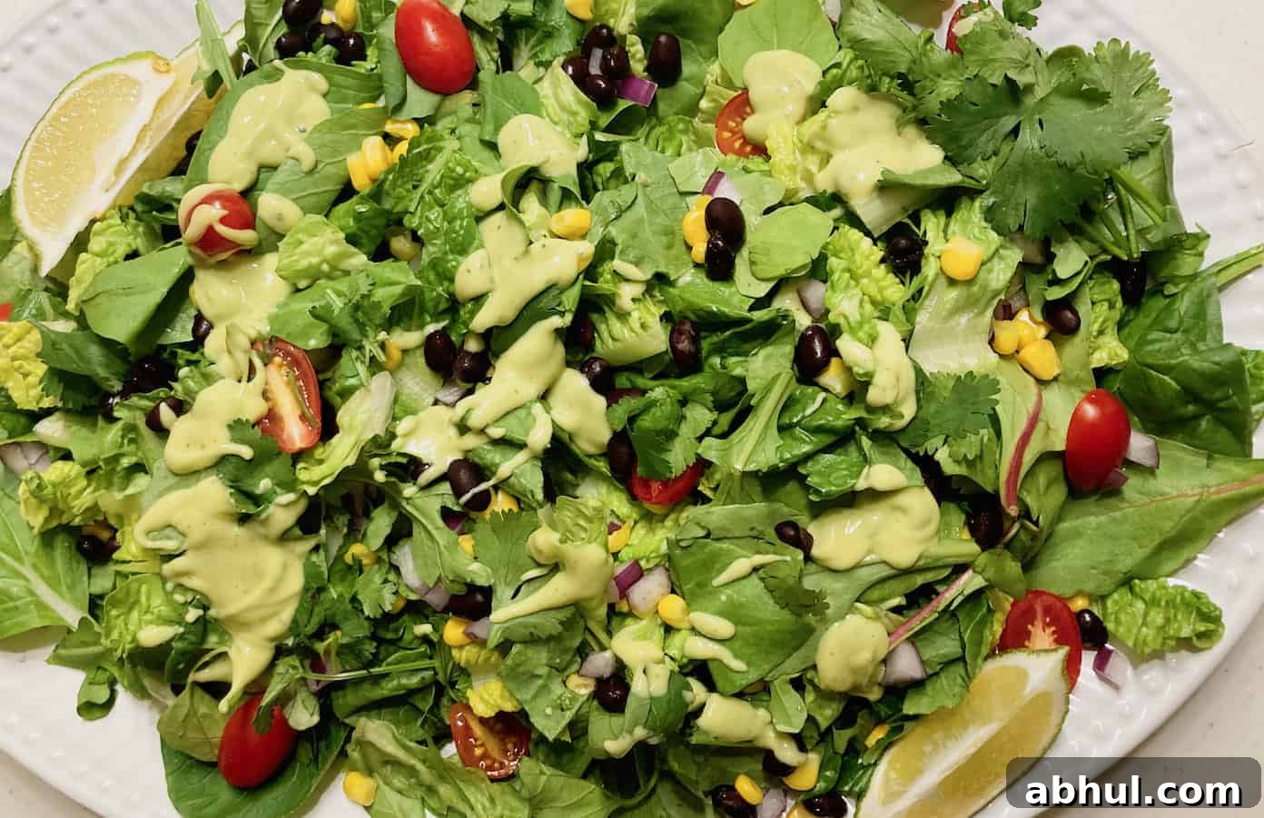 chopped greens with tomato, red onion, and corn topped with creamy avocado dressing