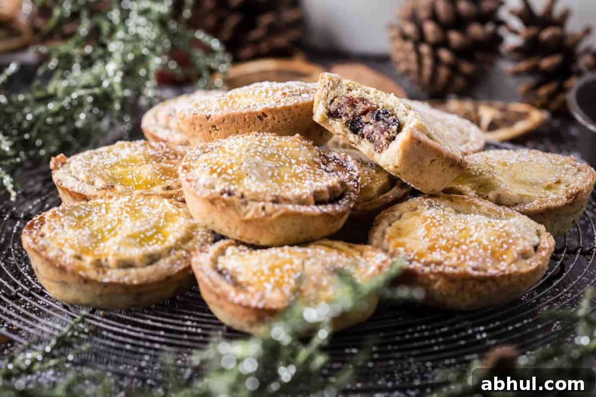 mince pies piled high with bite taken out of the top one showing juicy mincemeat filling.