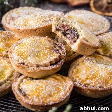 Gluten-Free Mince Pies on a wire rack with bite taken out of one showing the juicy mincemeat filling
