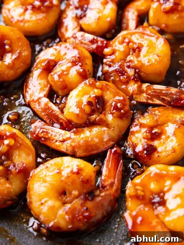 Close up of Asian garlic shrimp coated in a spicy and sweet Asian sauce packed with minced garlic, ginger, sriracha, chili oil, and sesame oil.
