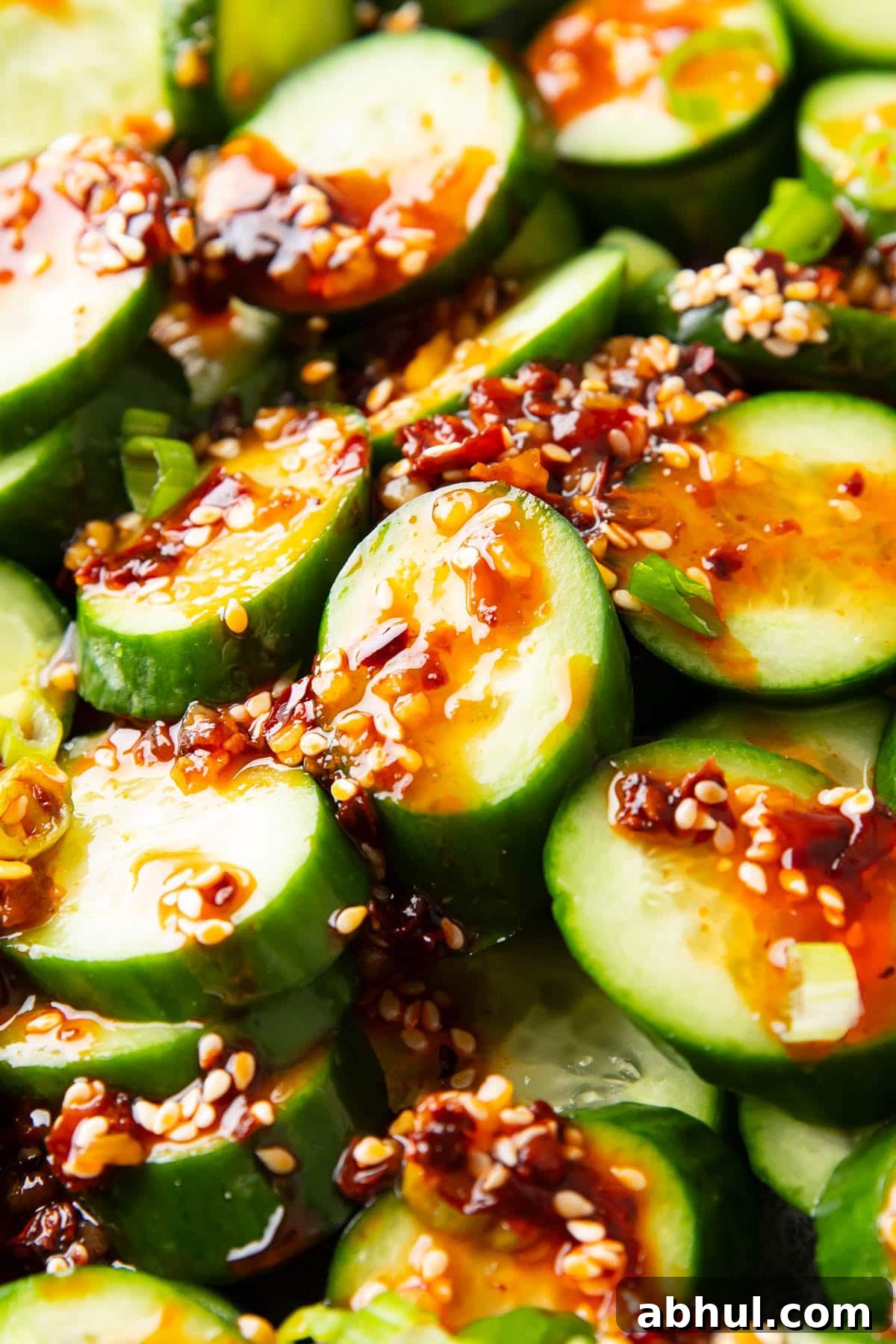 Close up of sesame and chili infused rice vinegar dressing poured over this Asian cucumber salad.