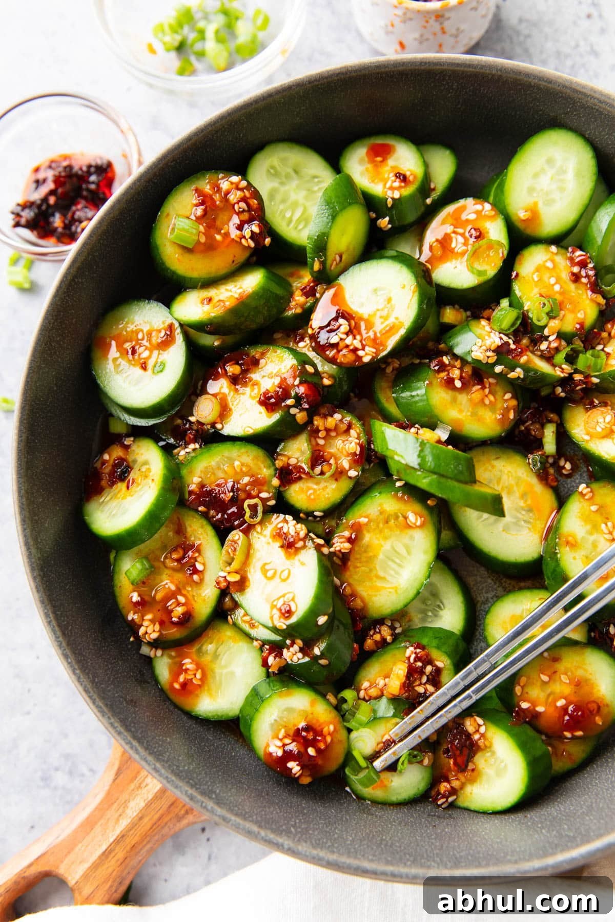Serving this refreshing Asian side dish packed with veggies in a bowl with sauce, toppings, and chopsticks on the side.