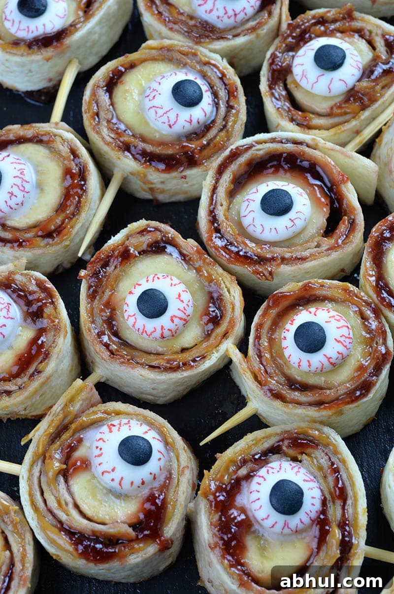 Bunch of Halloween Banana Sushi Rolls on a black plate.