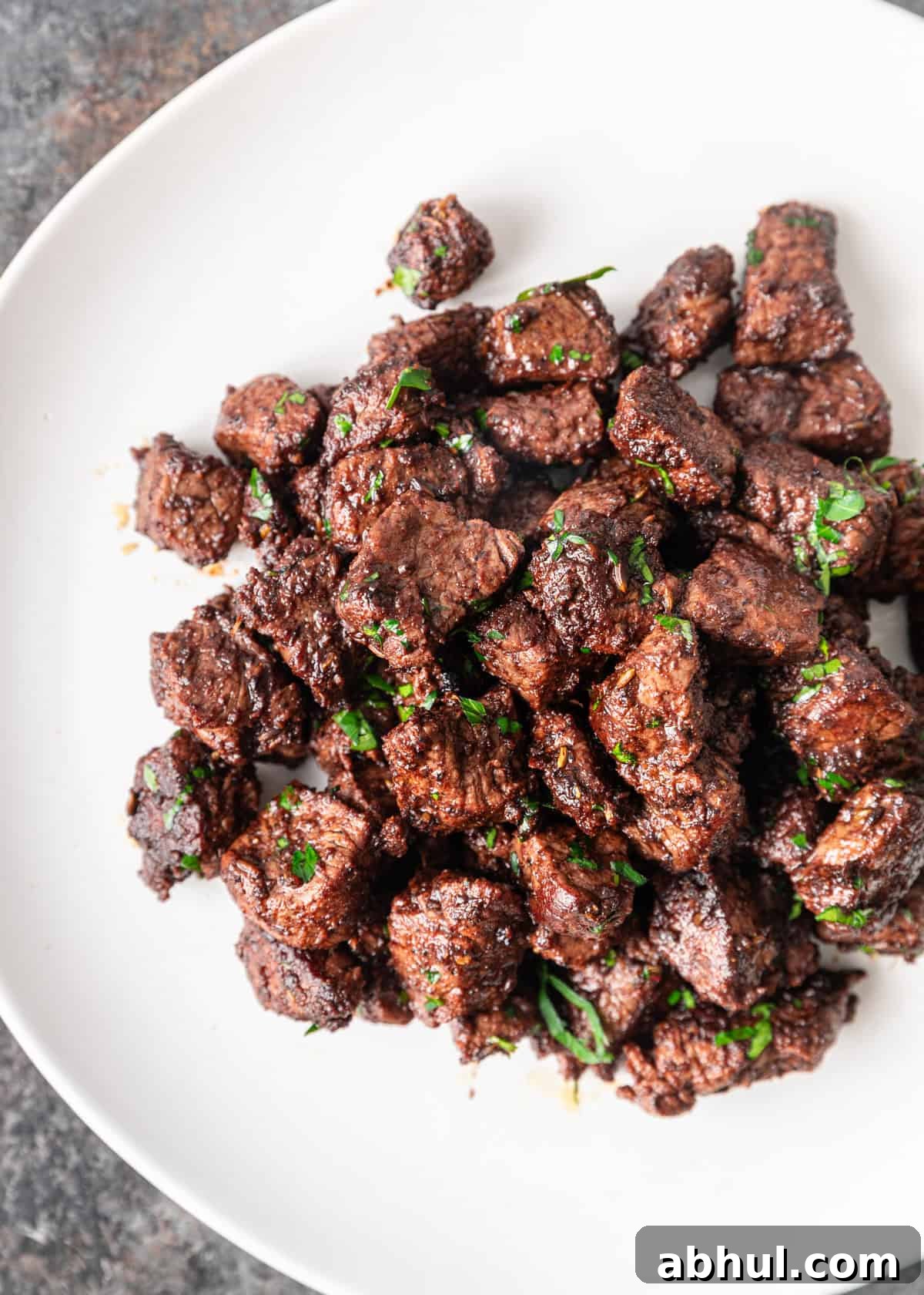 overhead closeup: plated blackened steak tips with fresh herbs on top