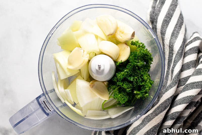 Overhead shot of a food processor with onion parsley and garlic in it
