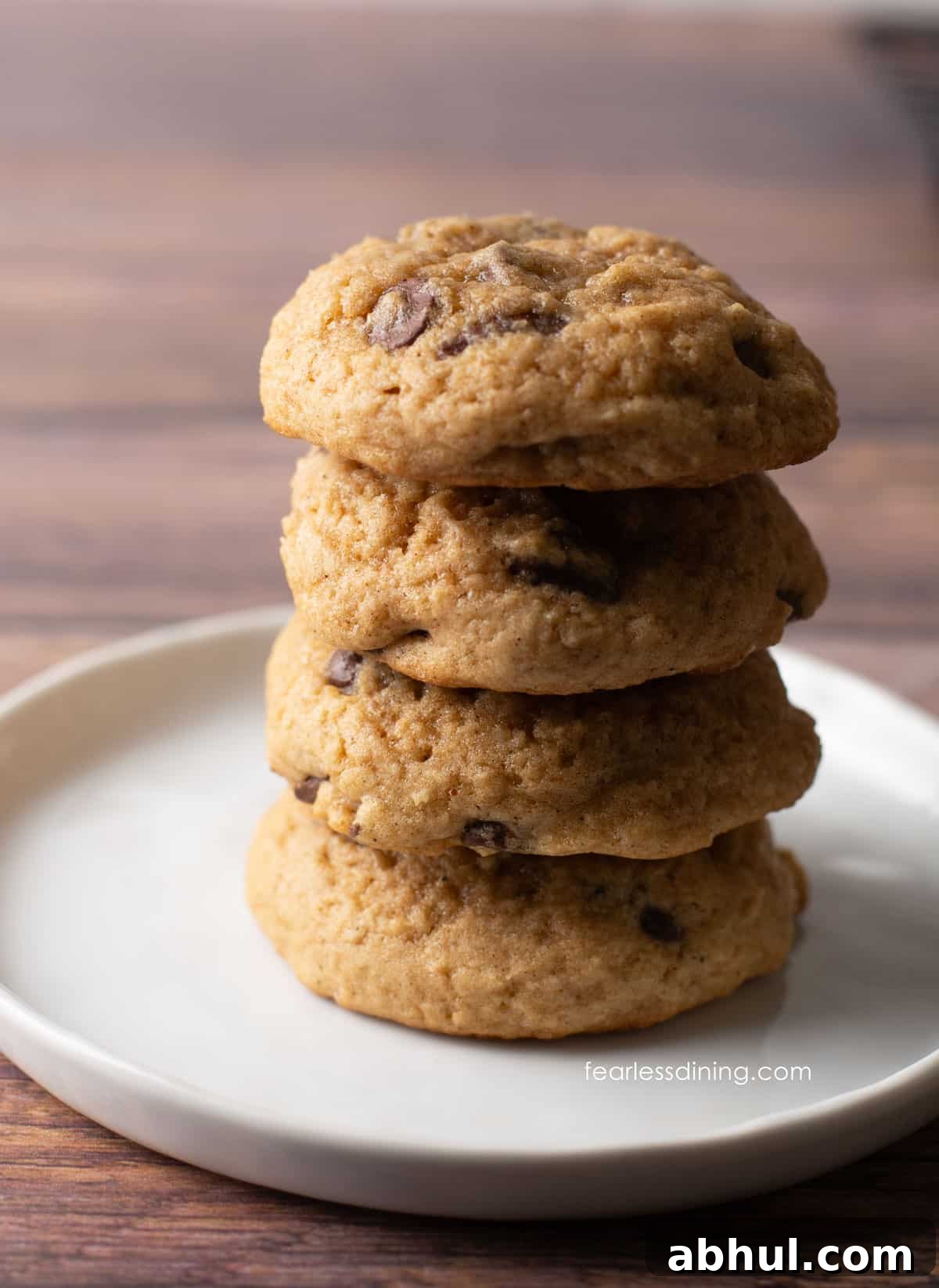 A stack of four gluten free eggnog chocolate chip cookies on a plate.
