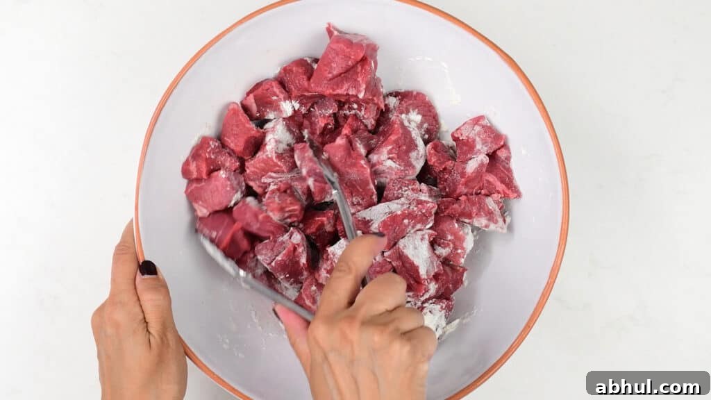 Tossing cubed beef with flour in a bowl