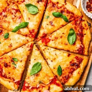A hand lifting a slice of high-protein cottage cheese pizza from a wooden cutting board.