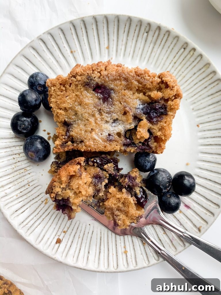 a muffin cut in half with melted butter on top and blueberries on the side