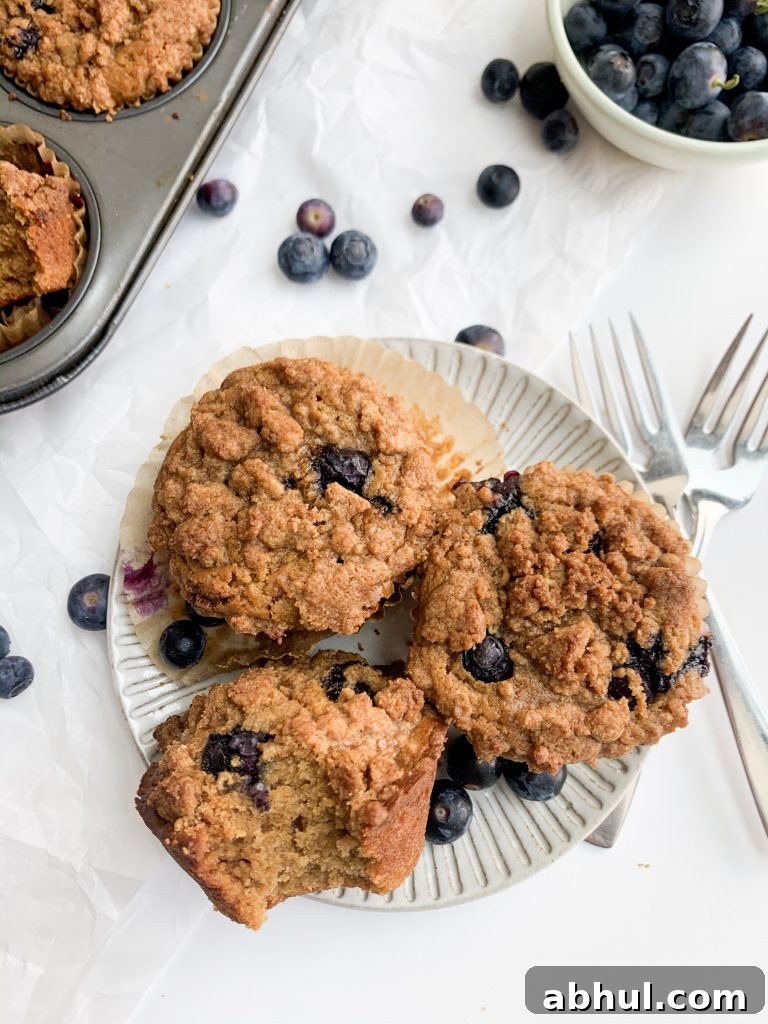 three blueberry crumb muffins on a grey plate