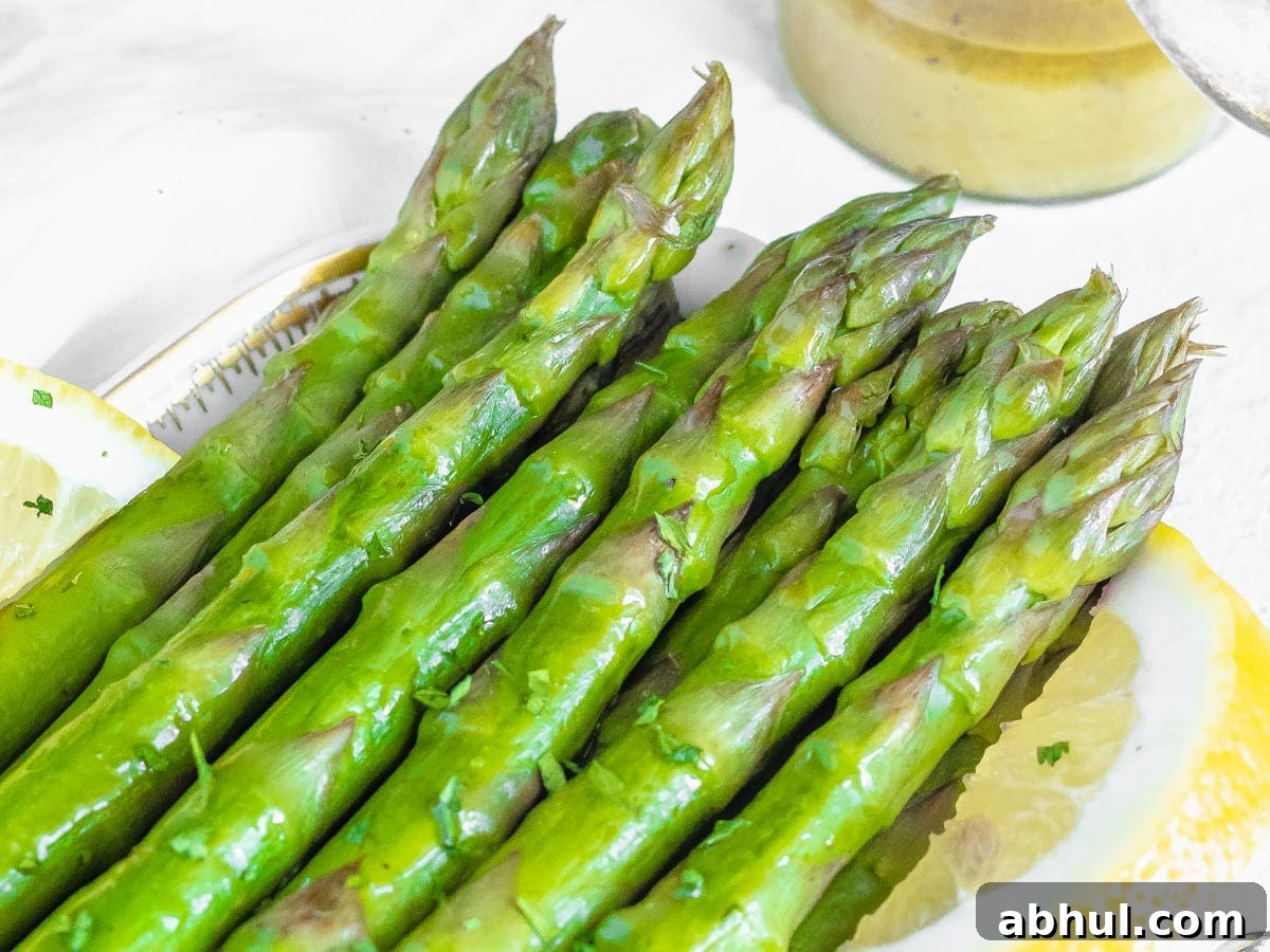 steamed asparagus served on a plate with lemon wedges