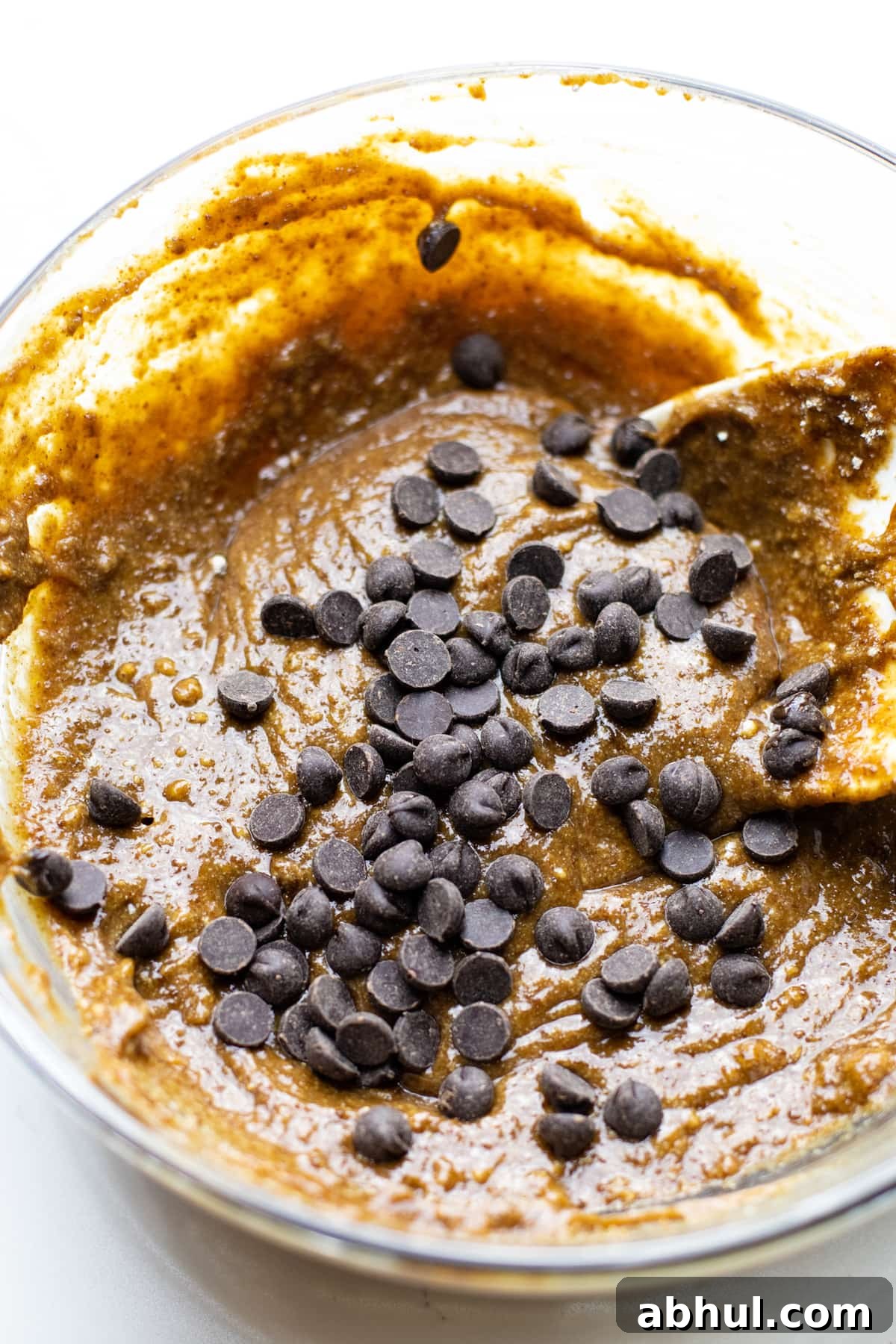 Oatmeal bar batter in a clear bowl with chocolate chips.