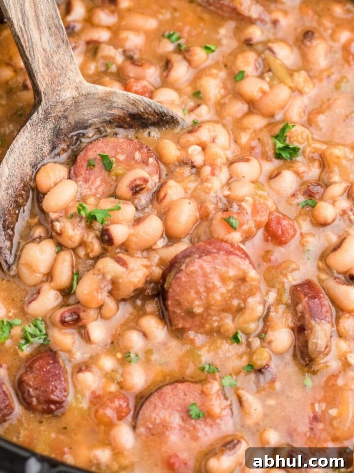 Close up shot cropped square, of a crock pot hoppin john with a spoon diggin in.