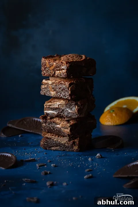 Chocolate orange brownies in a stack with orange slices in the background
