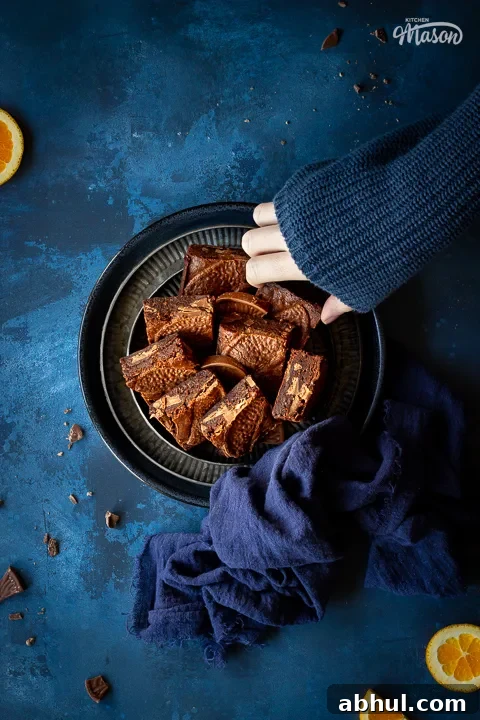 Someone taking fudgy orange brownies off a plate