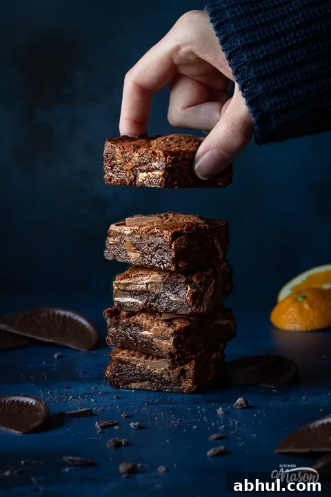 Someone taking a Terry's chocolate orange brownie off the top of a stack
